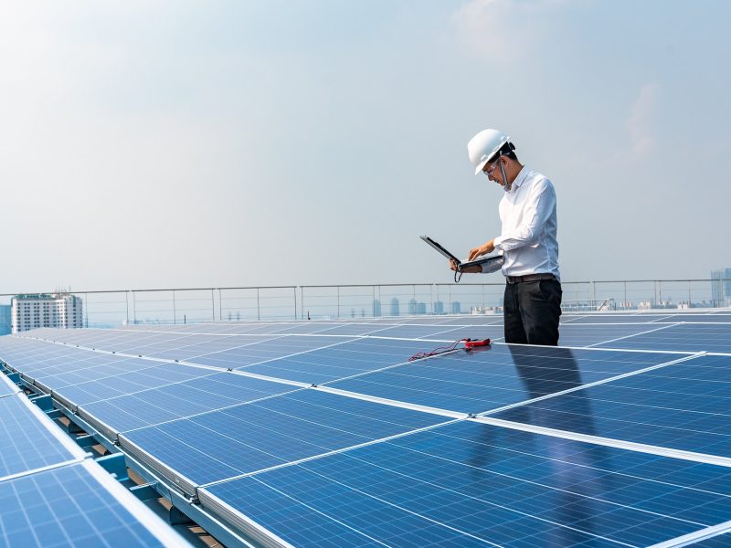 Electrical engineers are using laptops to monitor the operation of the solar rooftop. Renewable energy concepts.