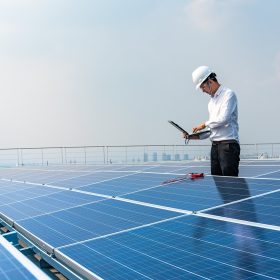 Electrical engineers are using laptops to monitor the operation of the solar rooftop. Renewable energy concepts.